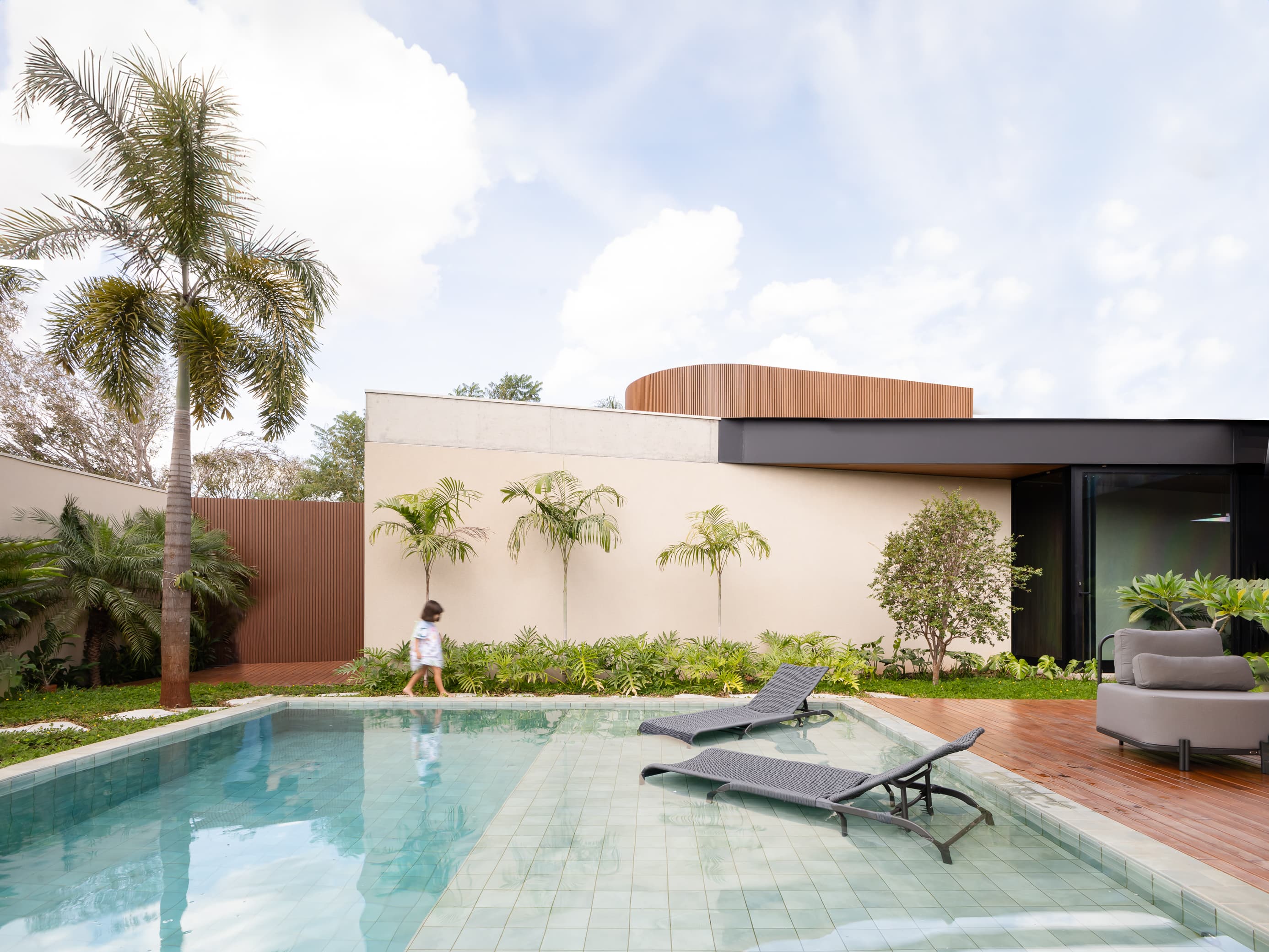Casa LuSi – fachada da residência com parede em concreto, palmeiras e ripas de madeira