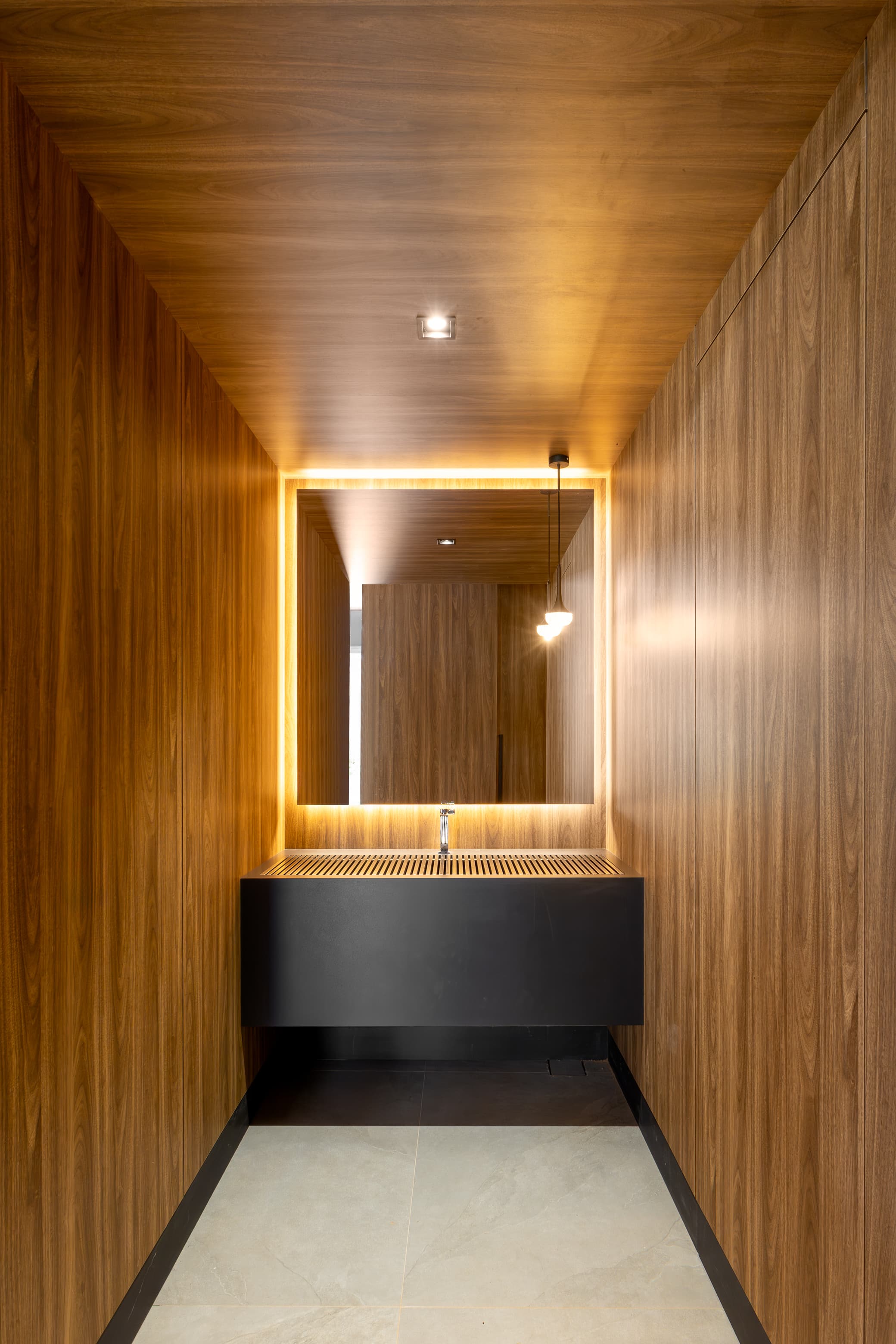 Casa LuSi – corredor interno com painéis de madeira e iluminação embutida