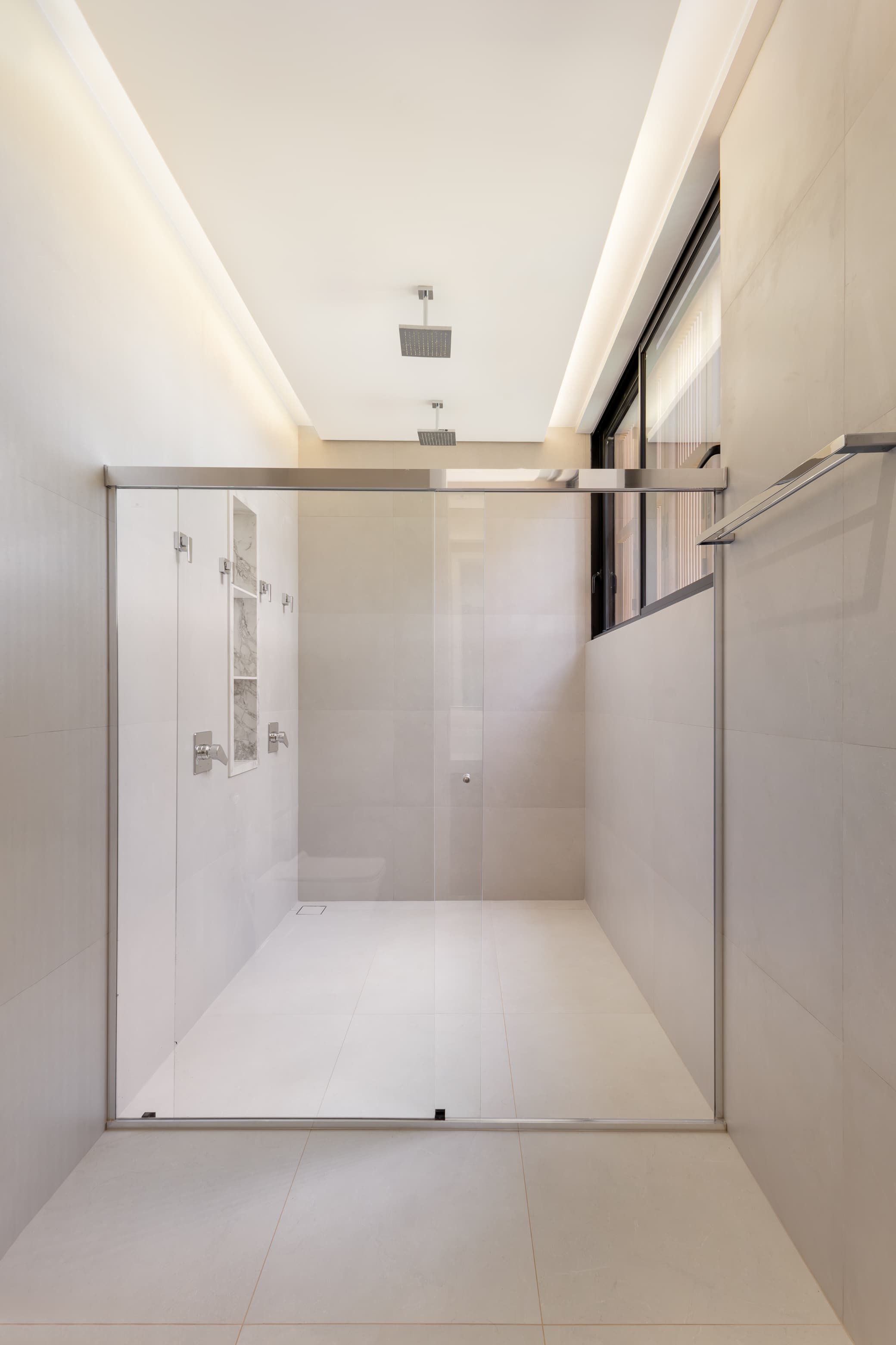 Casa LuSi – banheiro com revestimento em mármore claro e box de vidro