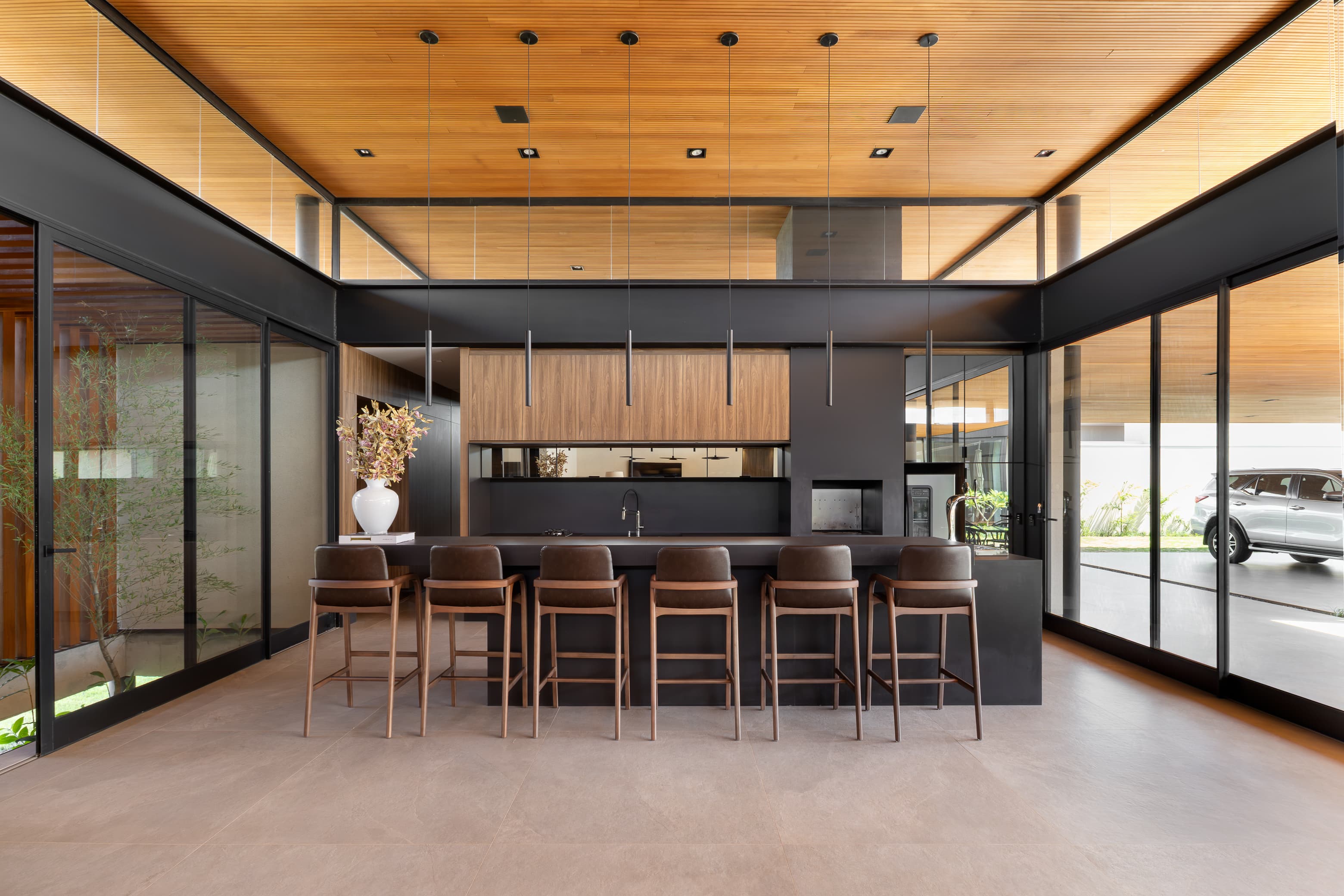 Casa LuSi – sala de jantar com mesa e cadeiras em couro, vista para cozinha e garagem