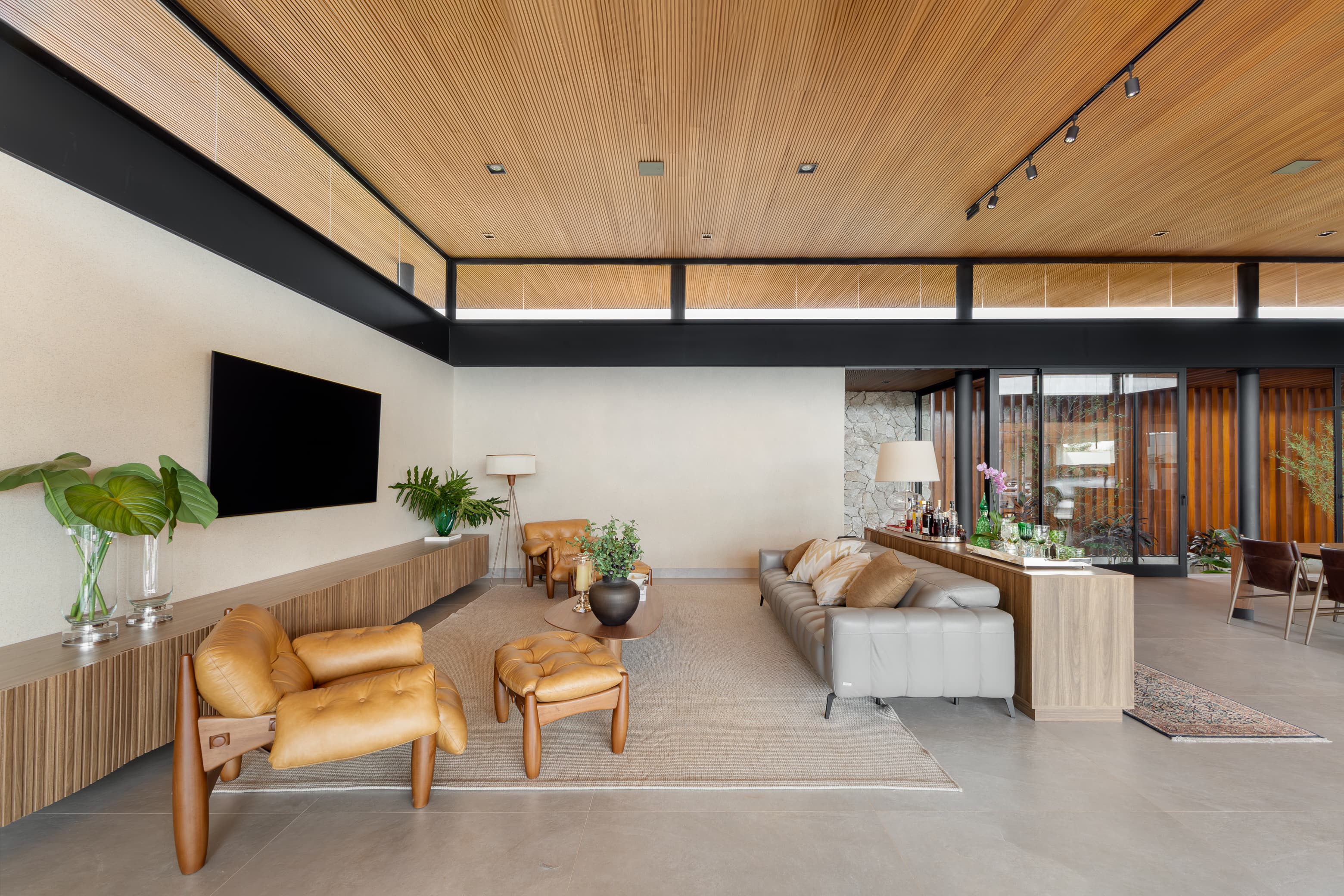Casa LuSi – sala de TV com painel, integrada à sala de estar e painéis de madeira