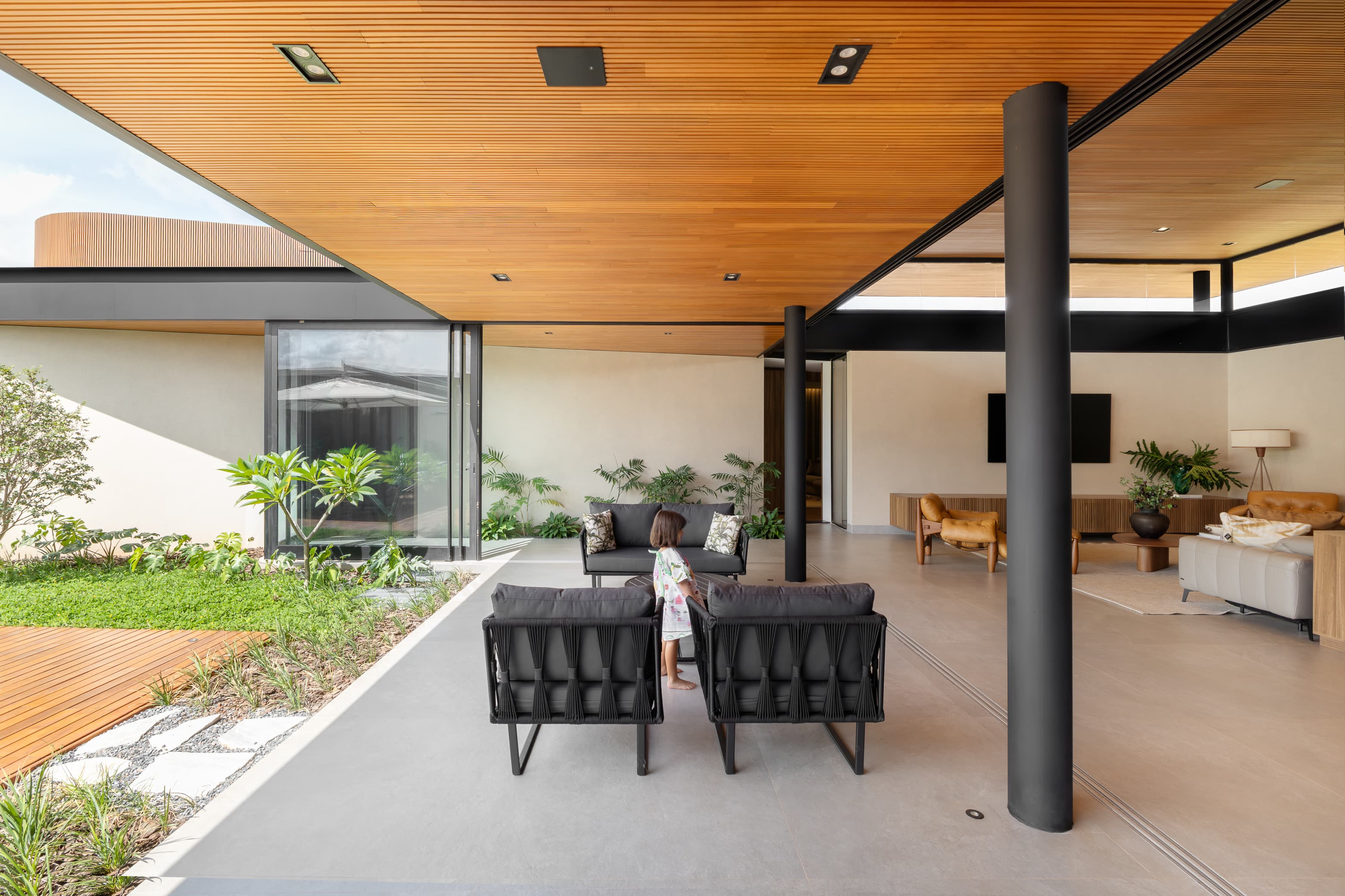 Casa LuSi – área de lazer coberta com sofás e jardim ao fundo