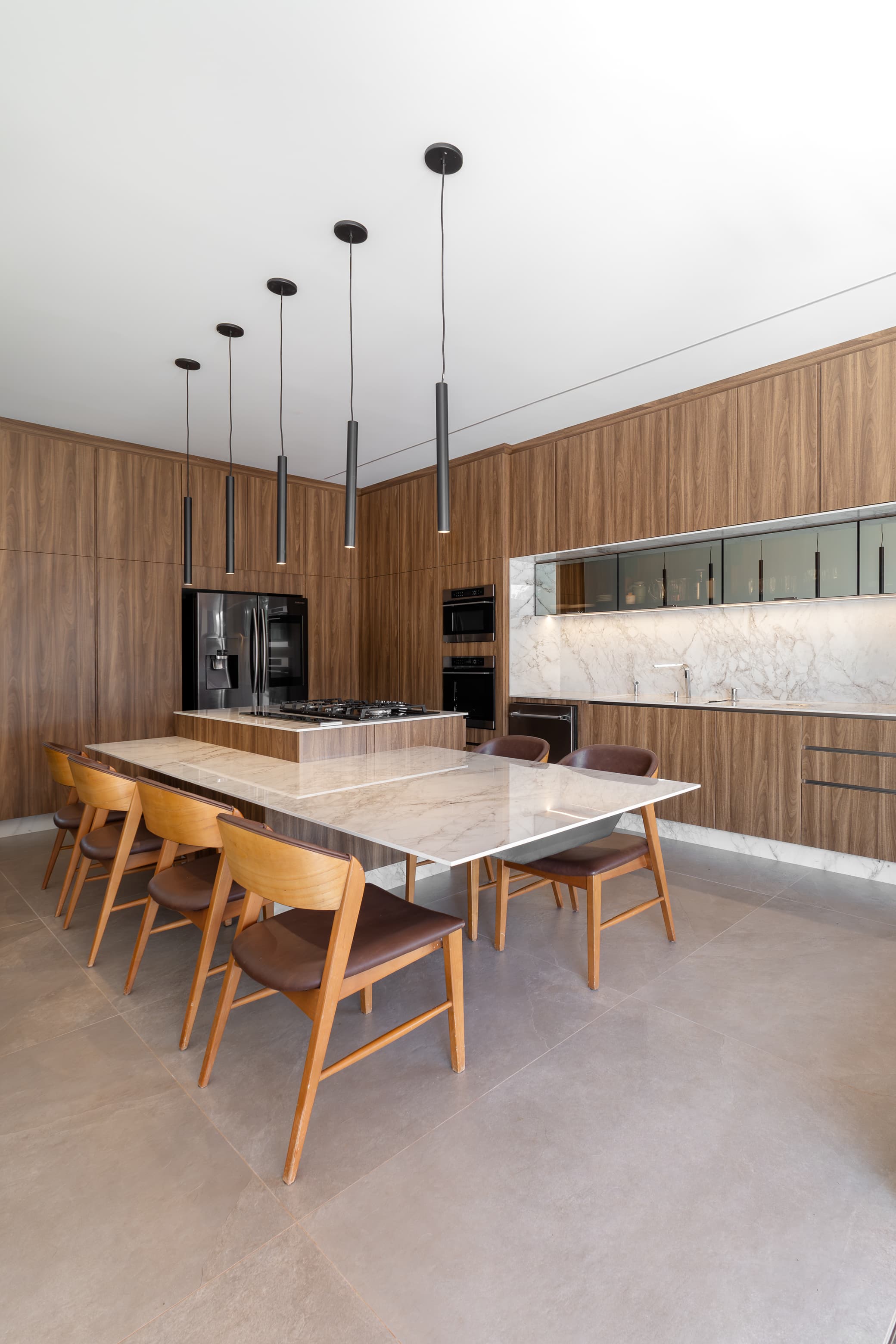 Casa LuSi – cozinha com ilha central, bancada em mármore e eletrodomésticos embutidos